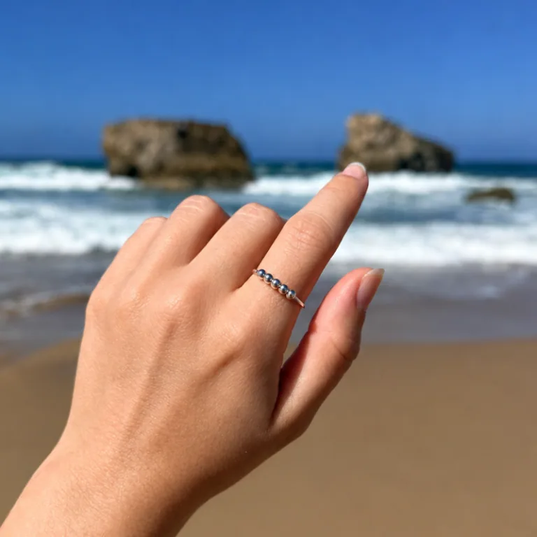 Main avec la bague anti-stress Valentina argentée sur la plage